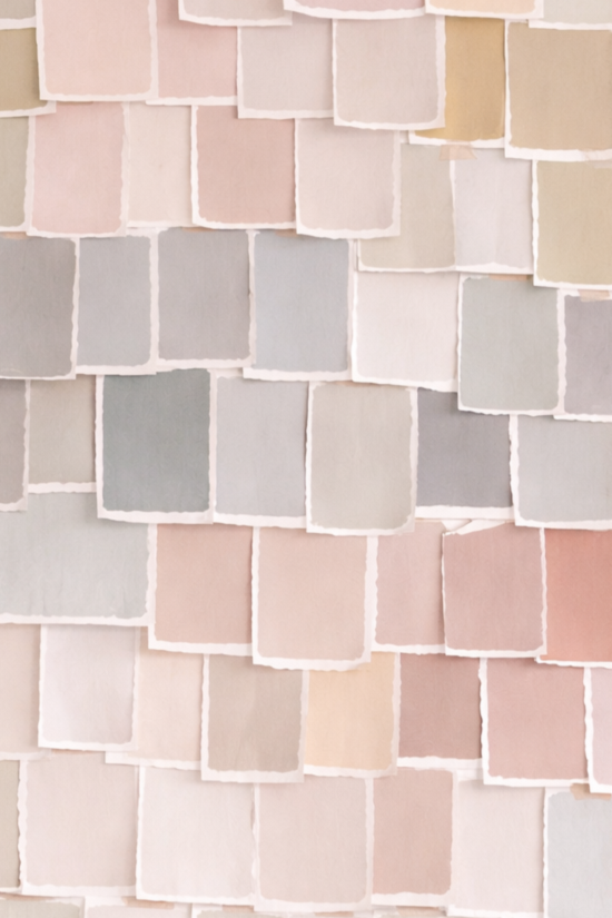 A collection of pastel colored paper squares arranged in overlapping layers on a wall.