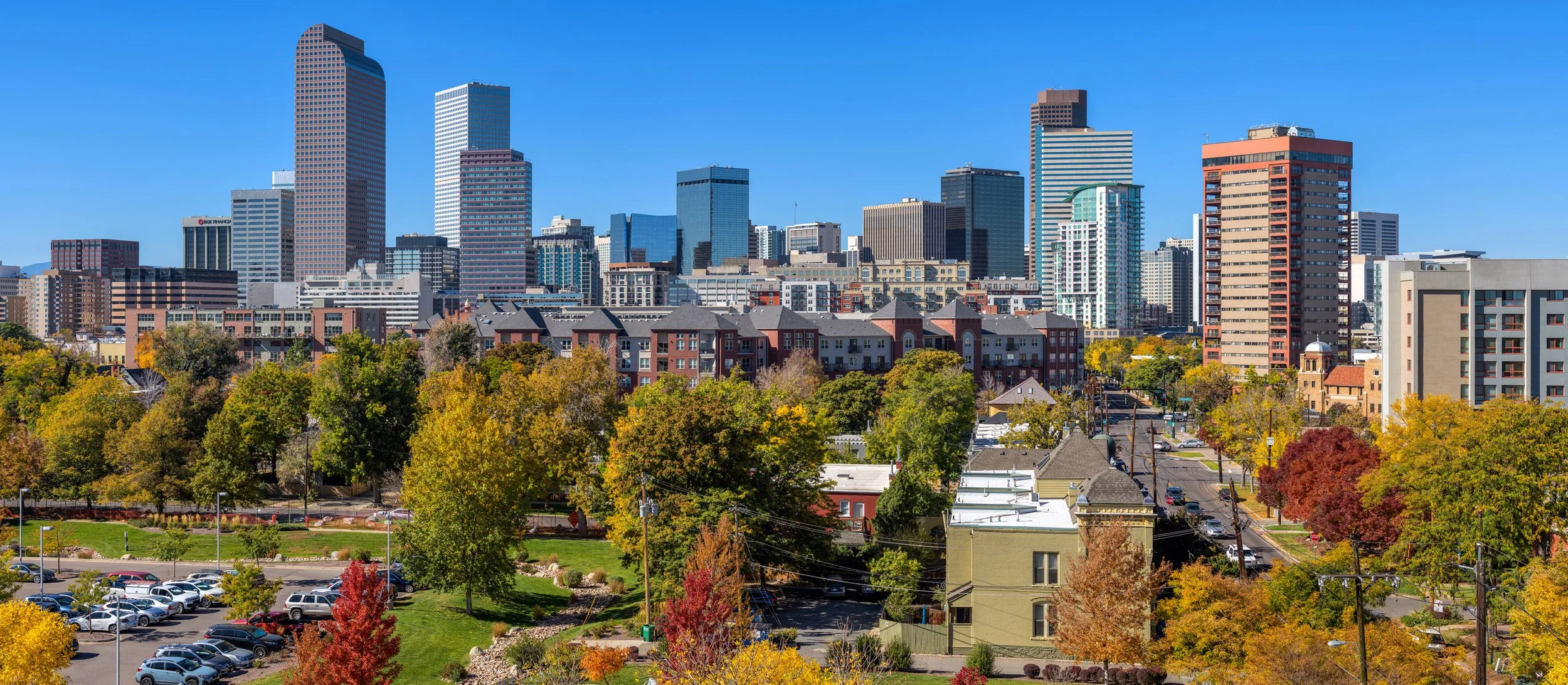 City skyline with high-rise buildings and colorful autumn trees in foreground on a sunny day