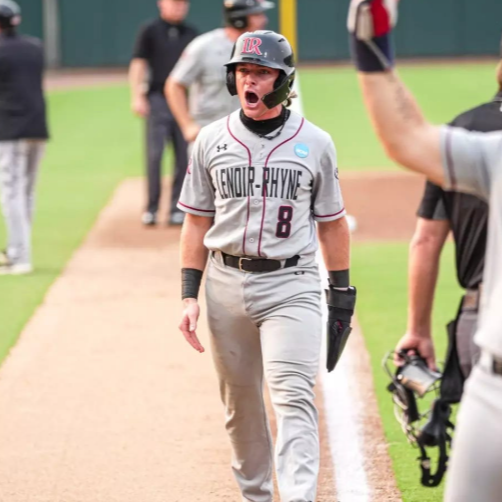 A female softball player in a gray uniform and helmet, number 8, celebrating at home plate during a game.