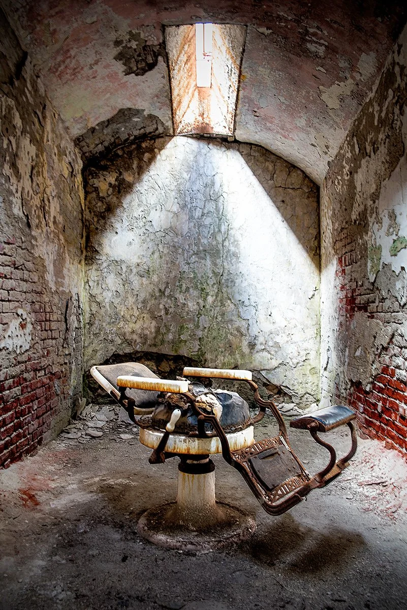 A dilapidated barber's chair sits amidst the cumbling plaster in a cell at Eastern State Penitentiary in Philadelphia