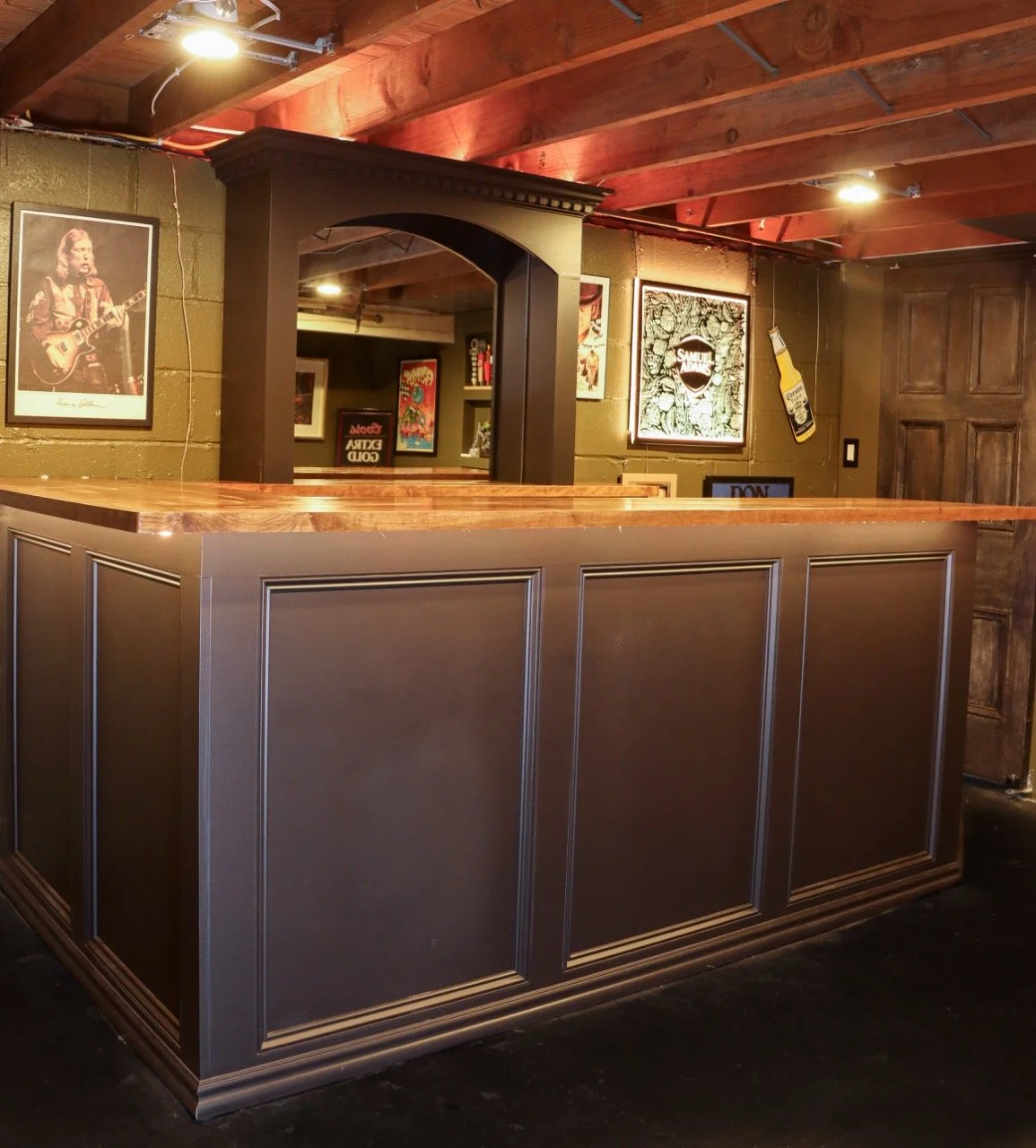 Bar with dark paneling, wooden countertop, and music posters on the brick wall.
