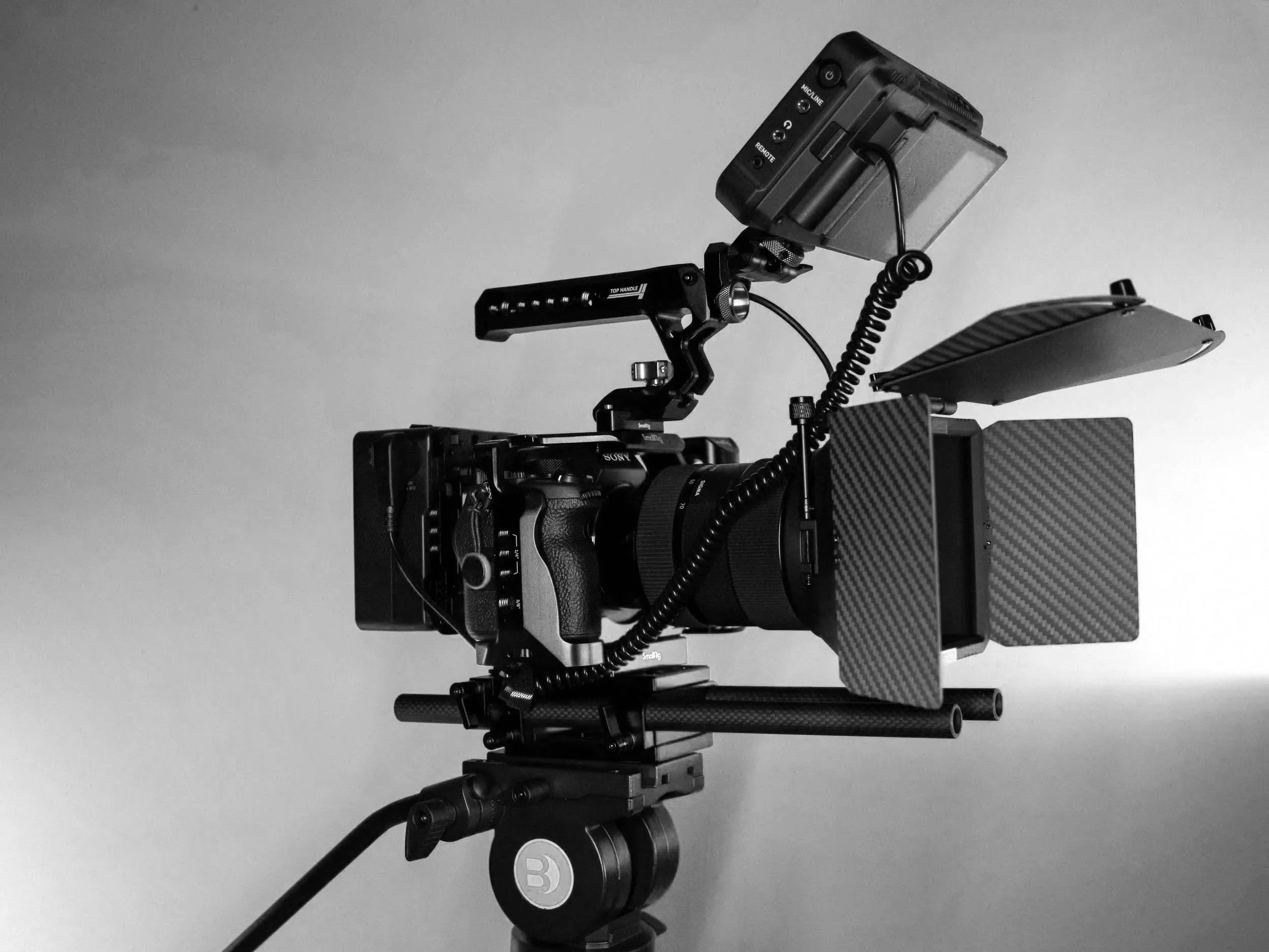 Et svart kamera utstyrt med flere tilbehør, satt opp på et stativ.