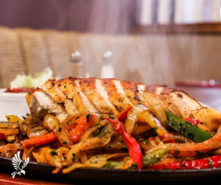 Grilled chicken and stir-fried vegetables on a plate with a blurred background.