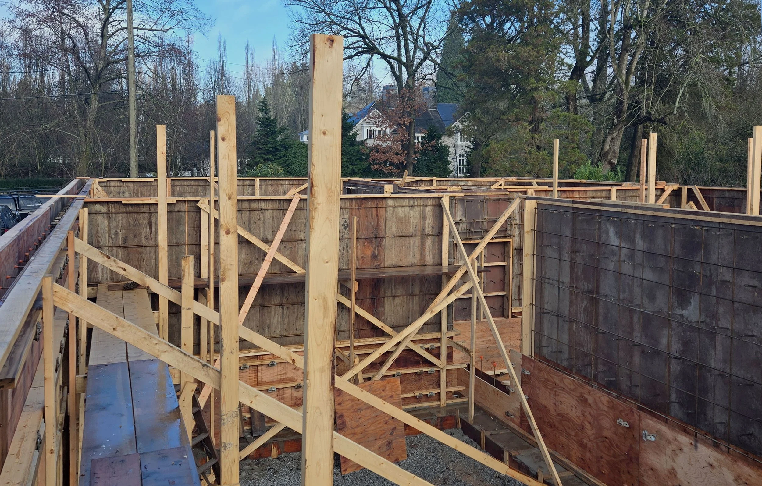 Wooden framing for the foundation of a building under construction, with wooden panels and support beams in an outdoor setting.