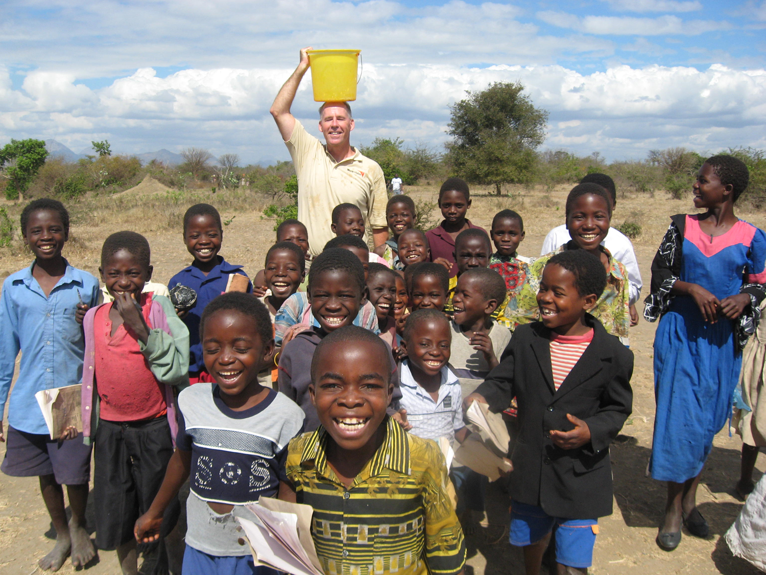 Greg with children and a bucket on his head