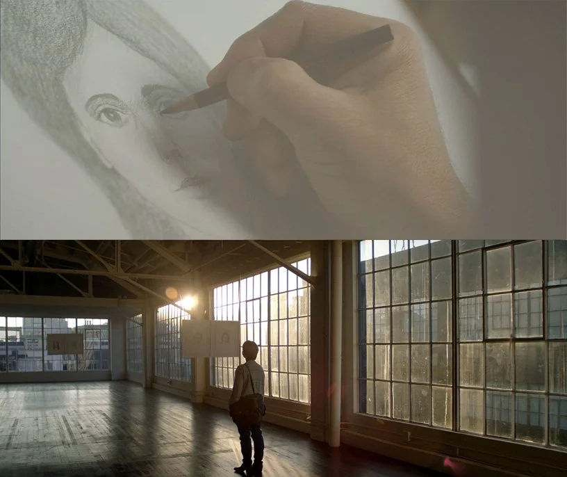 A person observing the sunset through large industrial-style windows in an empty, spacious room, with sunlight streaming in.