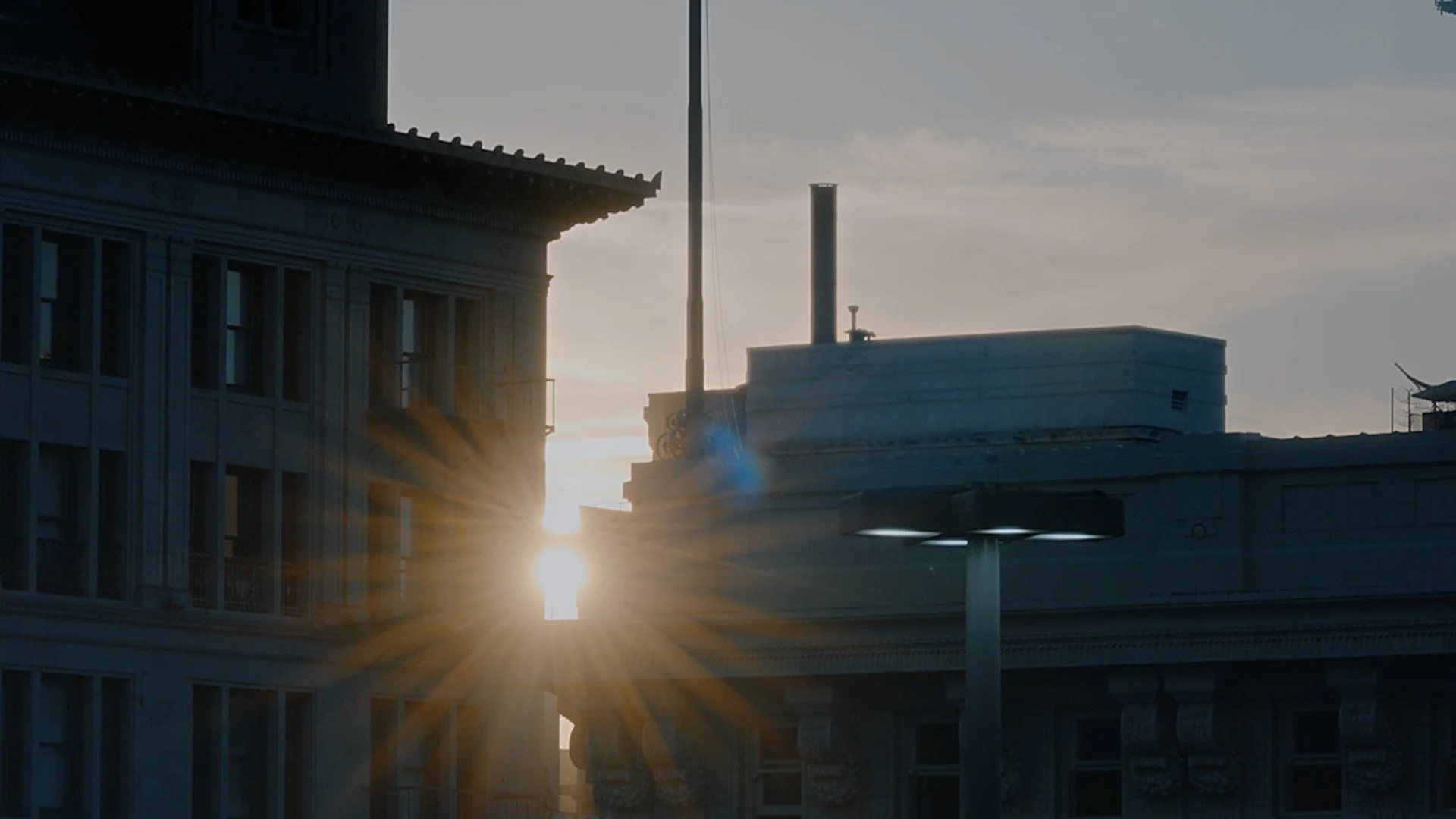 Sunset view between buildings with sun rays shining through.