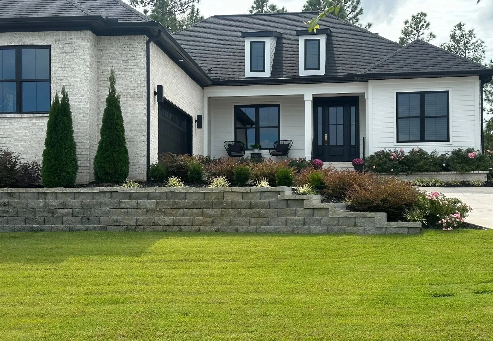 Person trimming a green bush with pruning shears while wearing gloves.