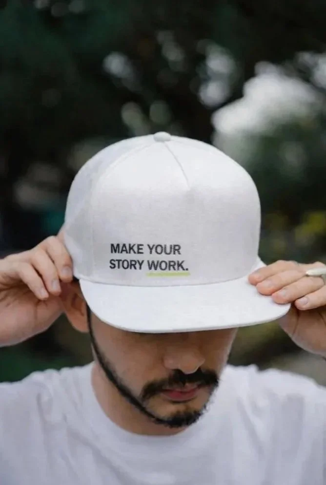 Influencer marketing with branded baseball cap with “Make Your Story Work” slogan in bold typography