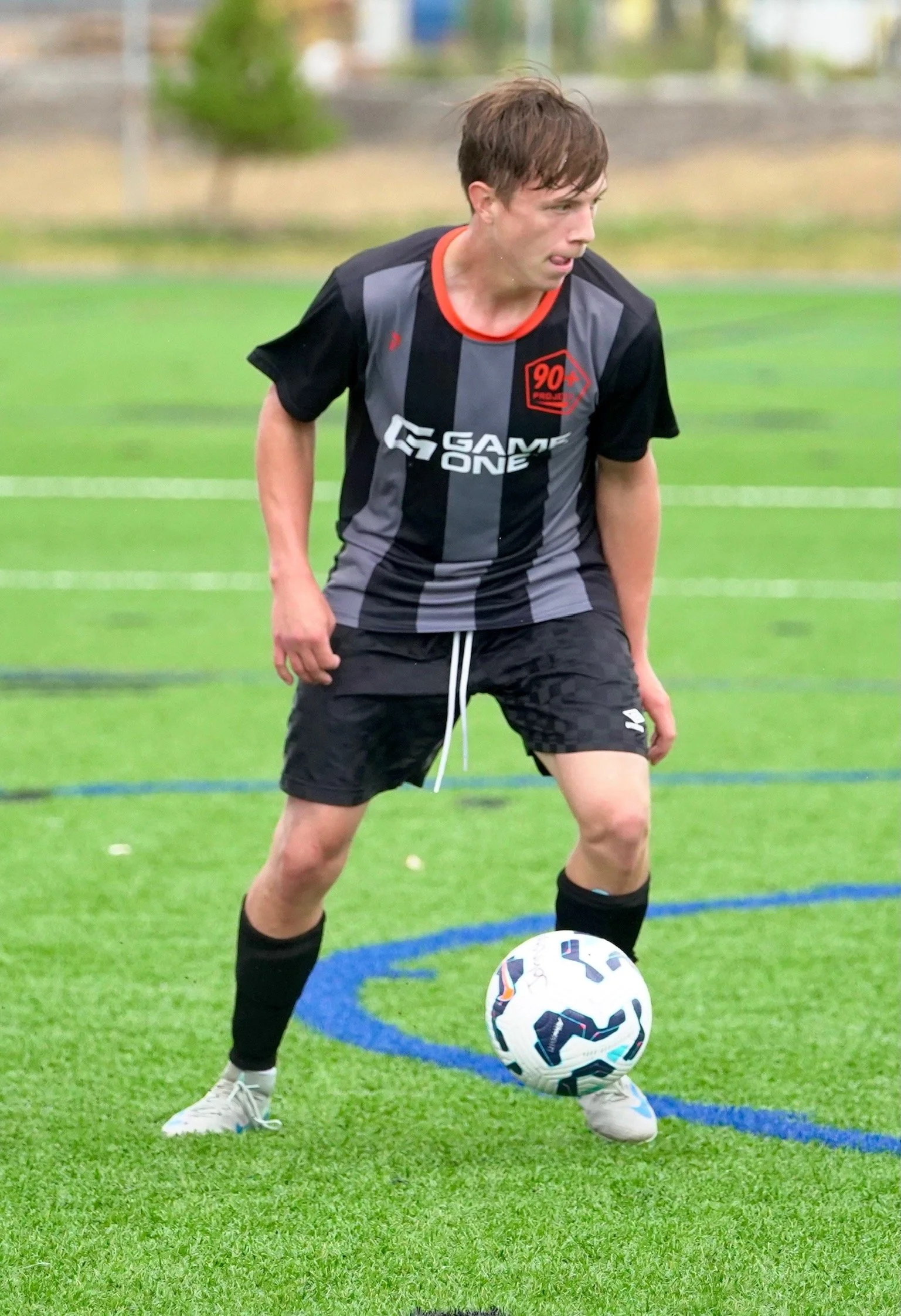 Young male soccer player is about to kick a soccer ball on a green field.