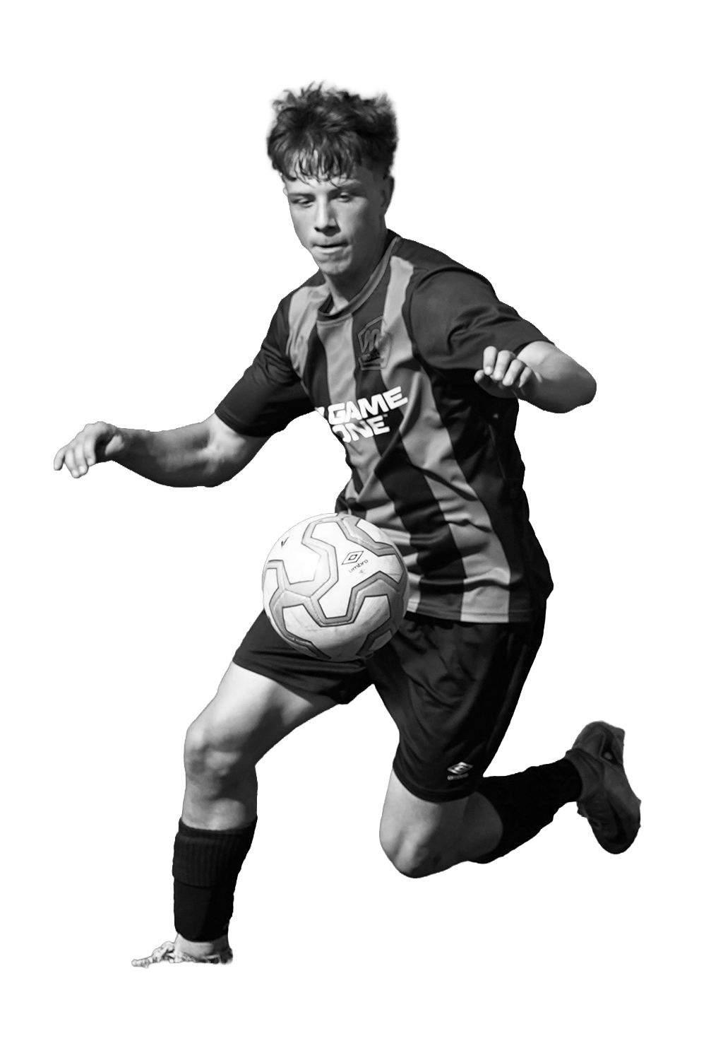 Black and white action shot of a young male soccer player in a striped jersey, running with a soccer ball at his knees.