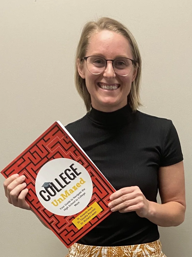 Smiling woman with glasses holding a red book titled "College UnMazed" in front of a plain beige wall, college counselor, school counselor, college and career readiness, curriculum, early college, dual enrollment