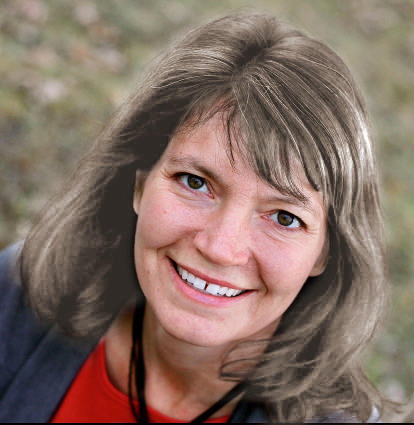 Smiling woman with shoulder-length brown hair outdoors.