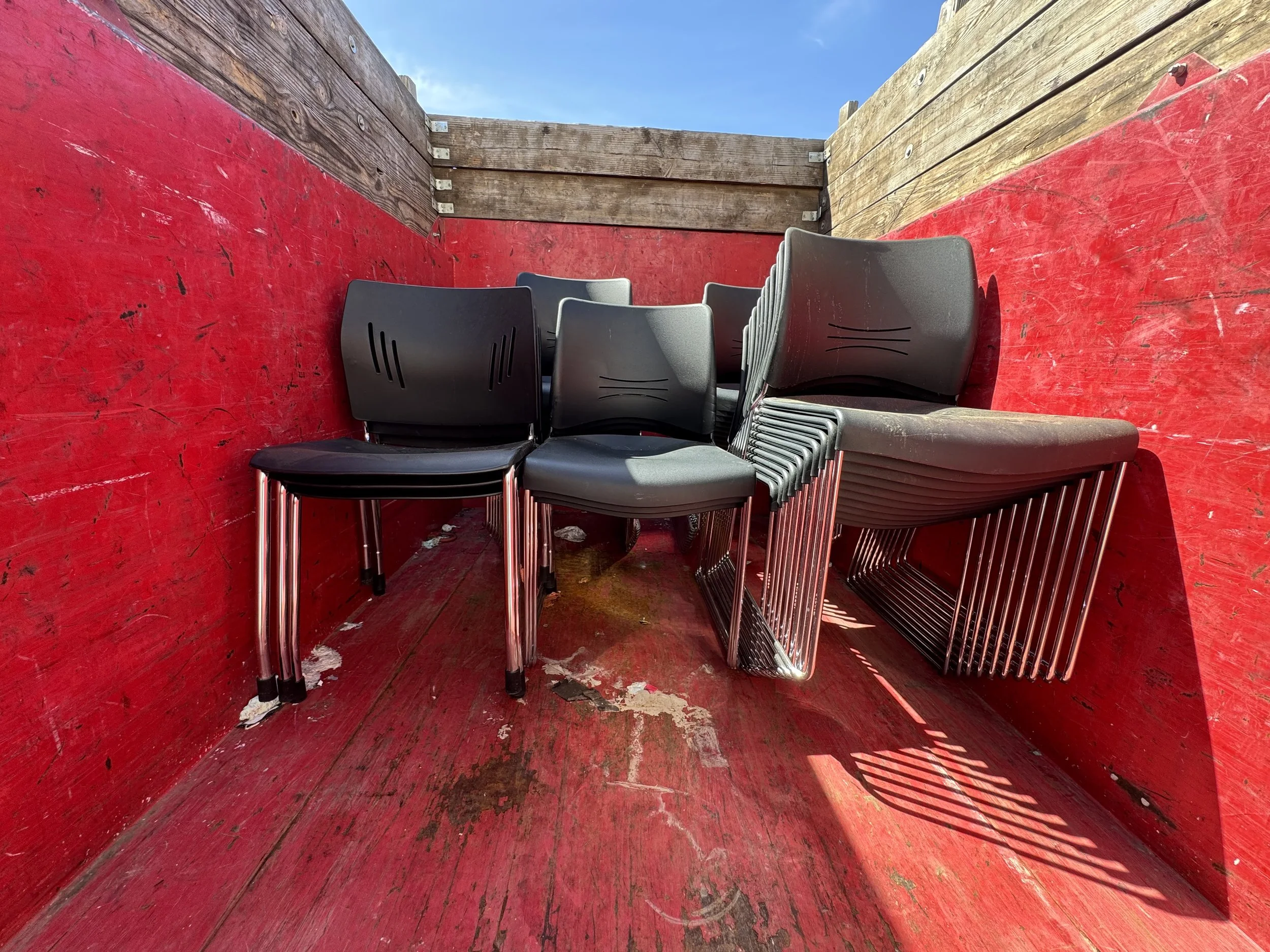 Black stackable chairs being delivered in a truck for audience seating at EnKore Theatre Company in Woodland, CA.