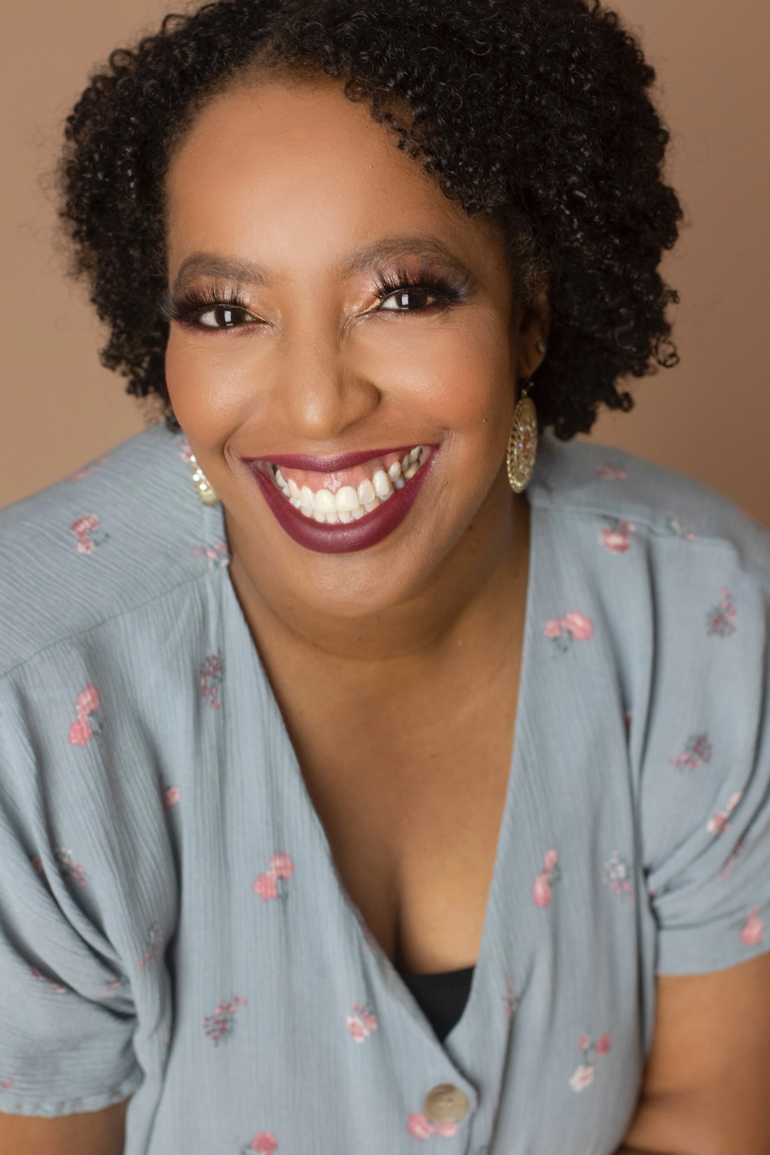 Portrait of Ronni La’Mar, House Manager for EnKore Theatre Company, smiling in a professional headshot while wearing a light blue floral blouse against a neutral background.