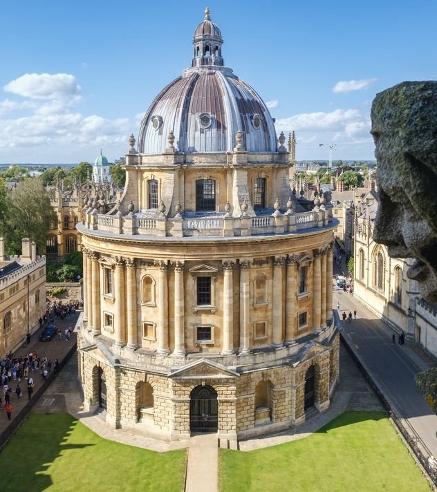 The Round Church, a historic circular stone building with a large domed roof, located in a city with other historic buildings and streets visible in the background.
