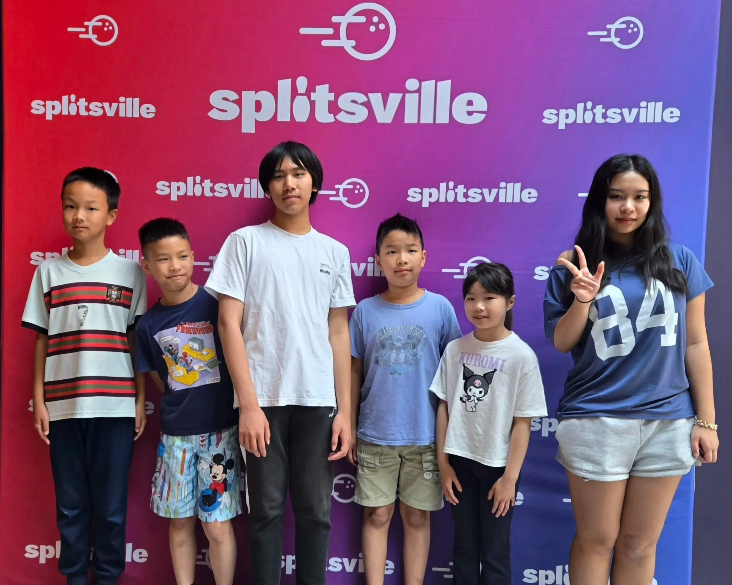 Group of six children standing in front of a red and purple backdrop with the word 'Splitsville' and a logo, posing for a photo.