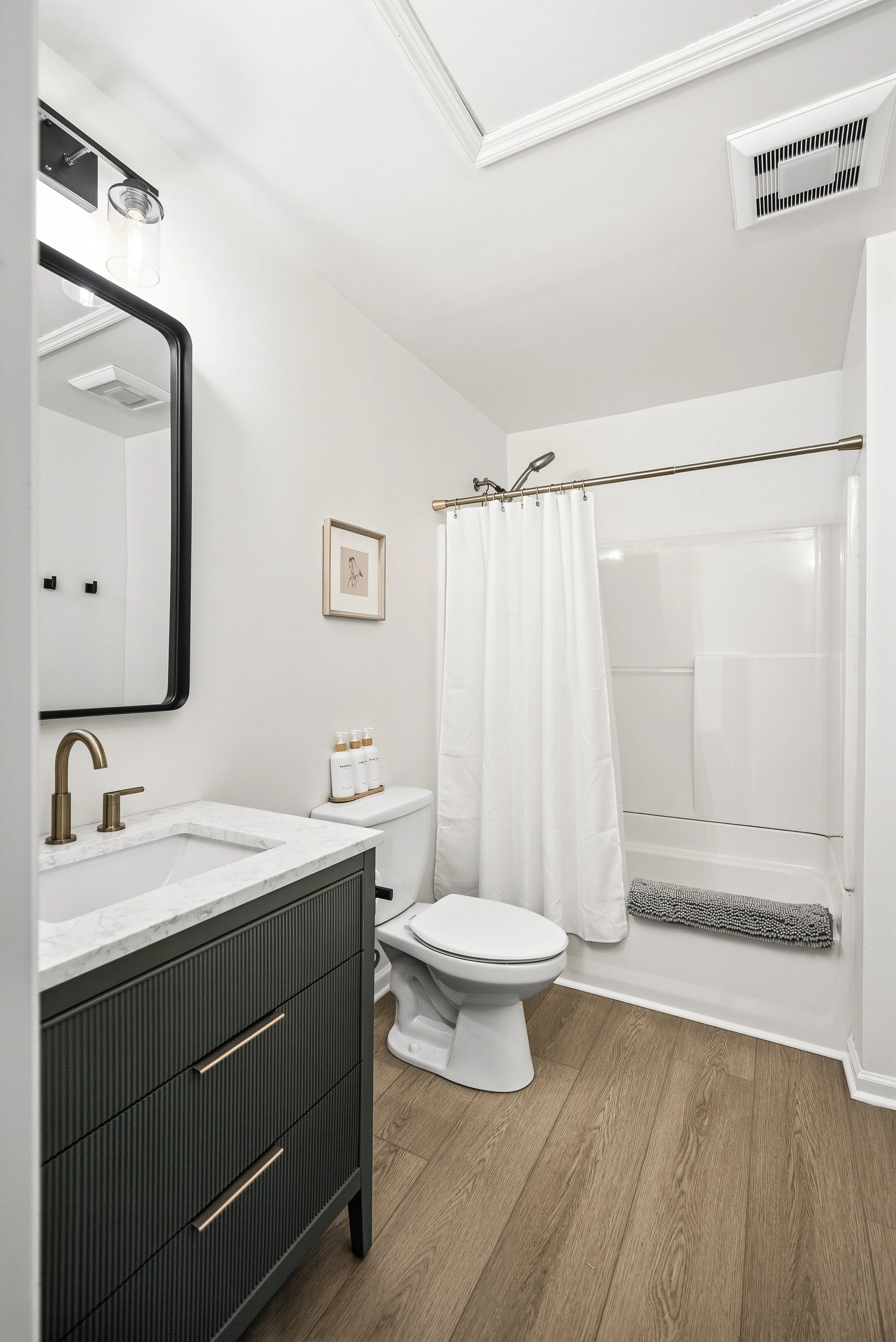 Updated bathroom with tub, detachable shower head, and bright lighting.