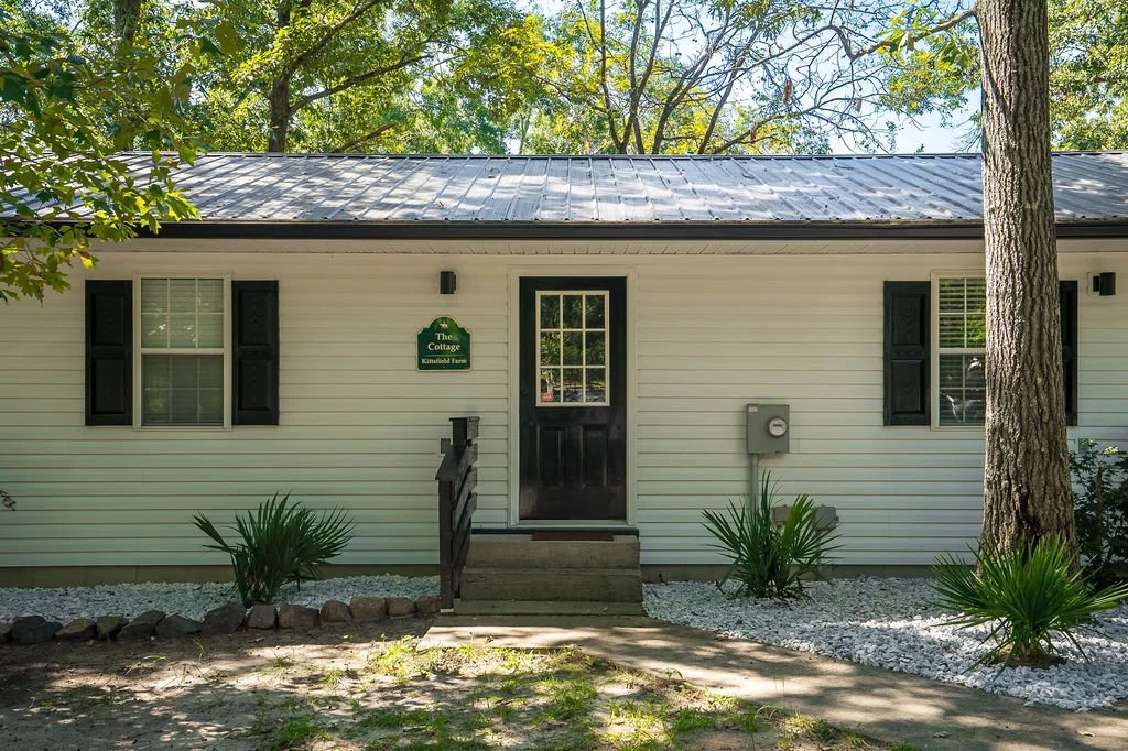 The Red Oak Cottage is nestled between the trees and the pasture