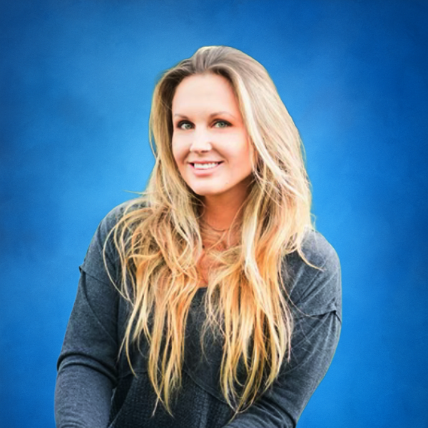 A smiling woman with long blonde hair wearing a dark gray top against a blue background.