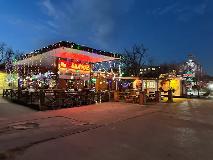 Exterior of a lively bar or restaurant decorated with colorful string lights at dusk.
