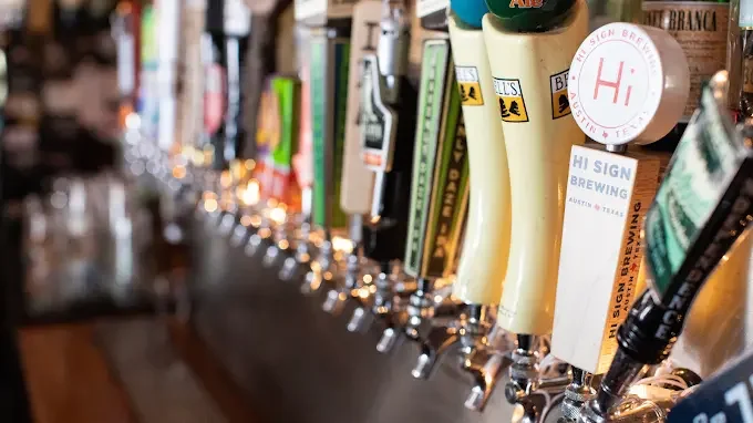 Beer taps at a bar with various beer brands and a Hi Sign Brewing tap handle.