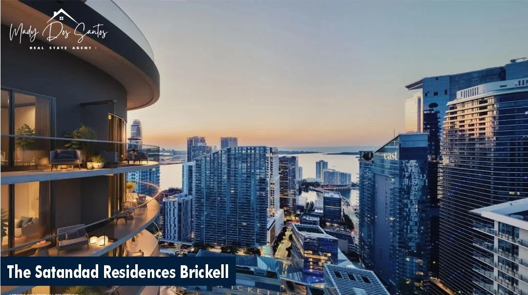 Vista del skyline de la ciudad desde un balcón de residencias de lujo en The Satandad Residences Brickell al atardecer, con edificios altos y un cuerpo de agua al fondo.