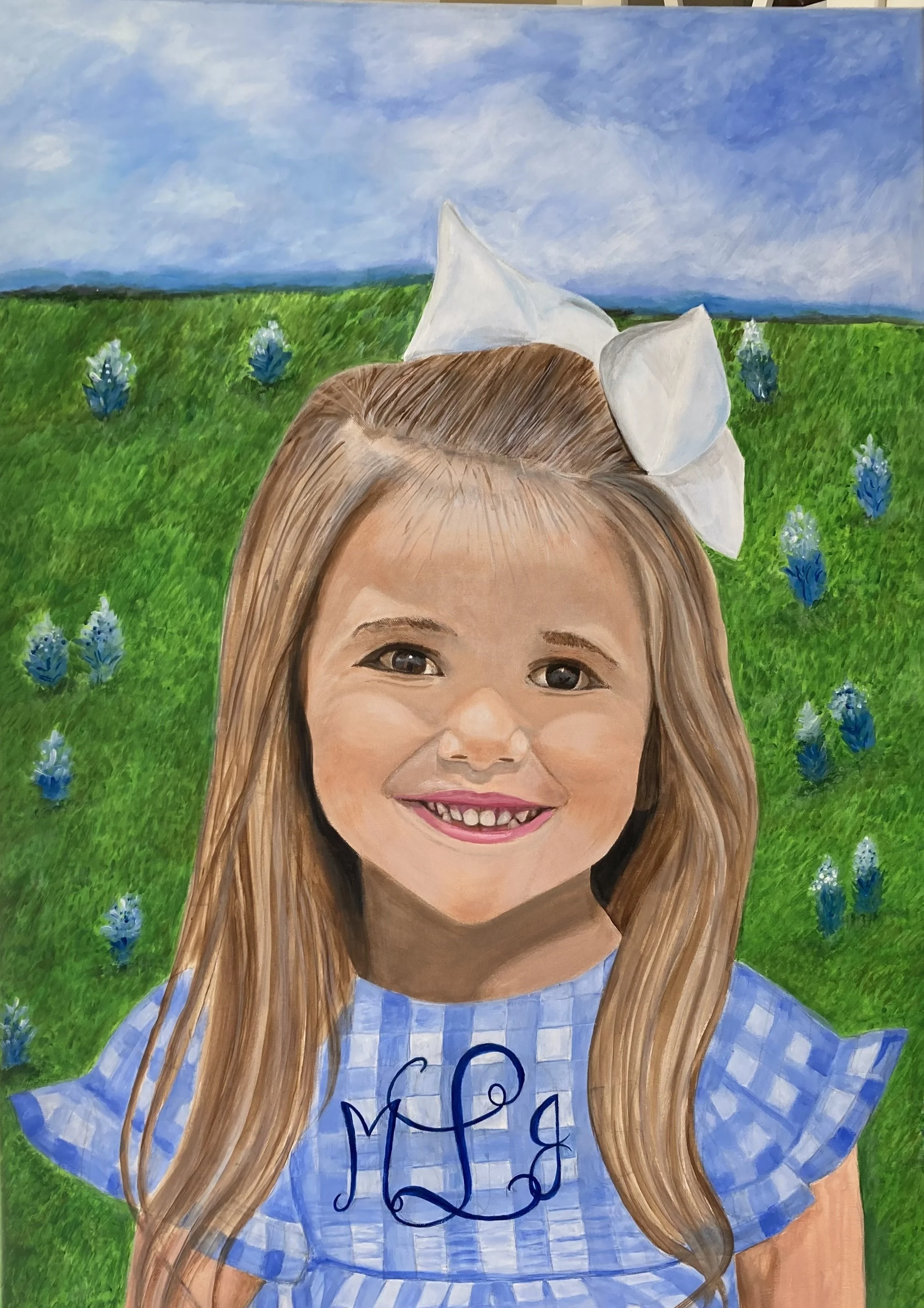 A portrait of a young girl with long brown hair, smiling with missing front teeth, wearing a blue and white gingham dress and a large white bow in her hair, standing in a field of green grass with blue flowers under a partly cloudy sky.