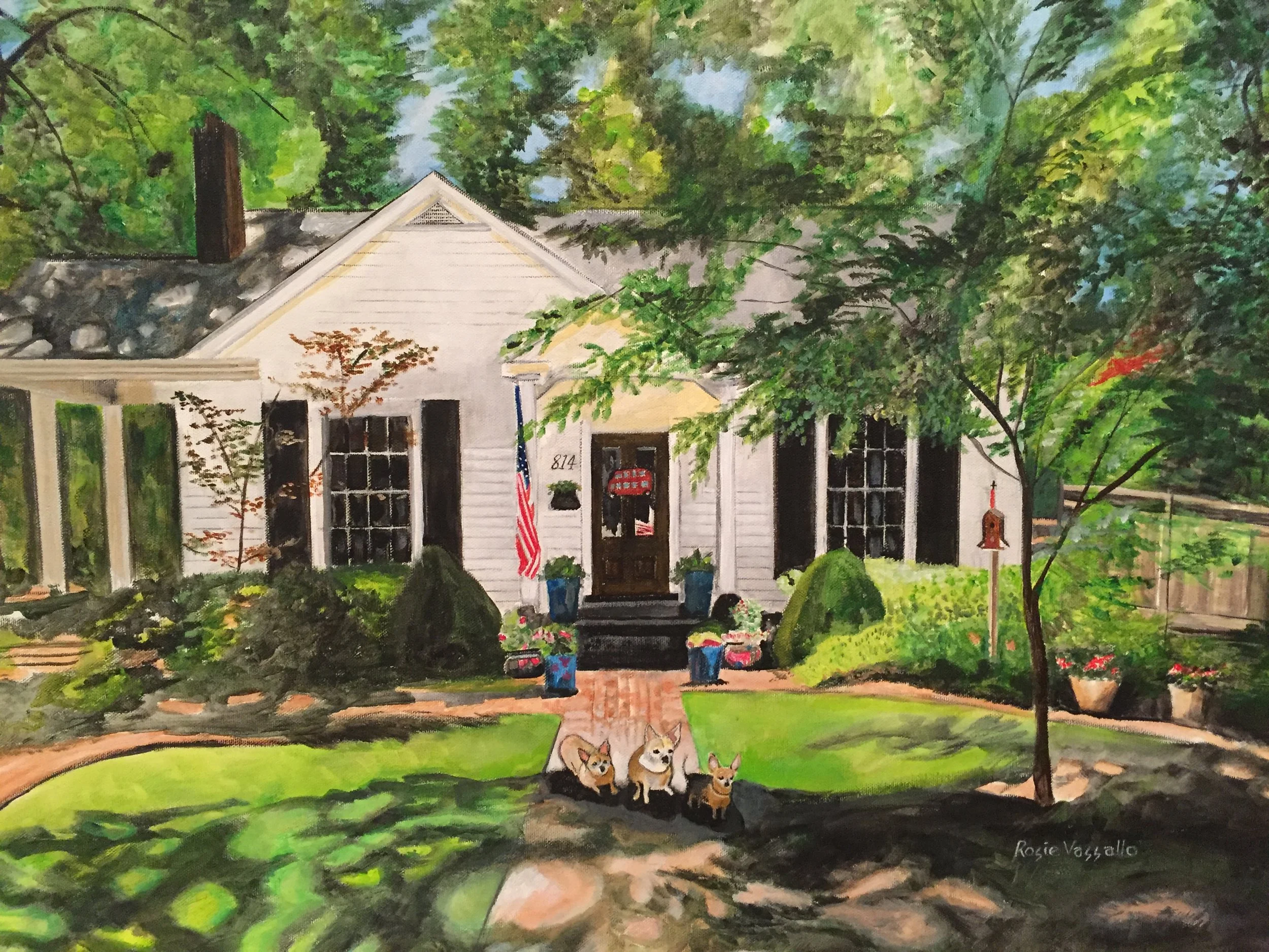 Painting of a white house with black shutters surrounded by lush green trees and shrubs. Front yard features a brick pathway, potted plants, and a small group of three dogs sitting on the grass. The house has a flag, a mailbox, and a birdhouse near t