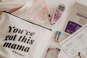 Flat lay of a tote bag with the text 'You're got this mama', a pink toy phone, a pair of baby socks, a digital thermometer, and a box of electronic medical supplies.