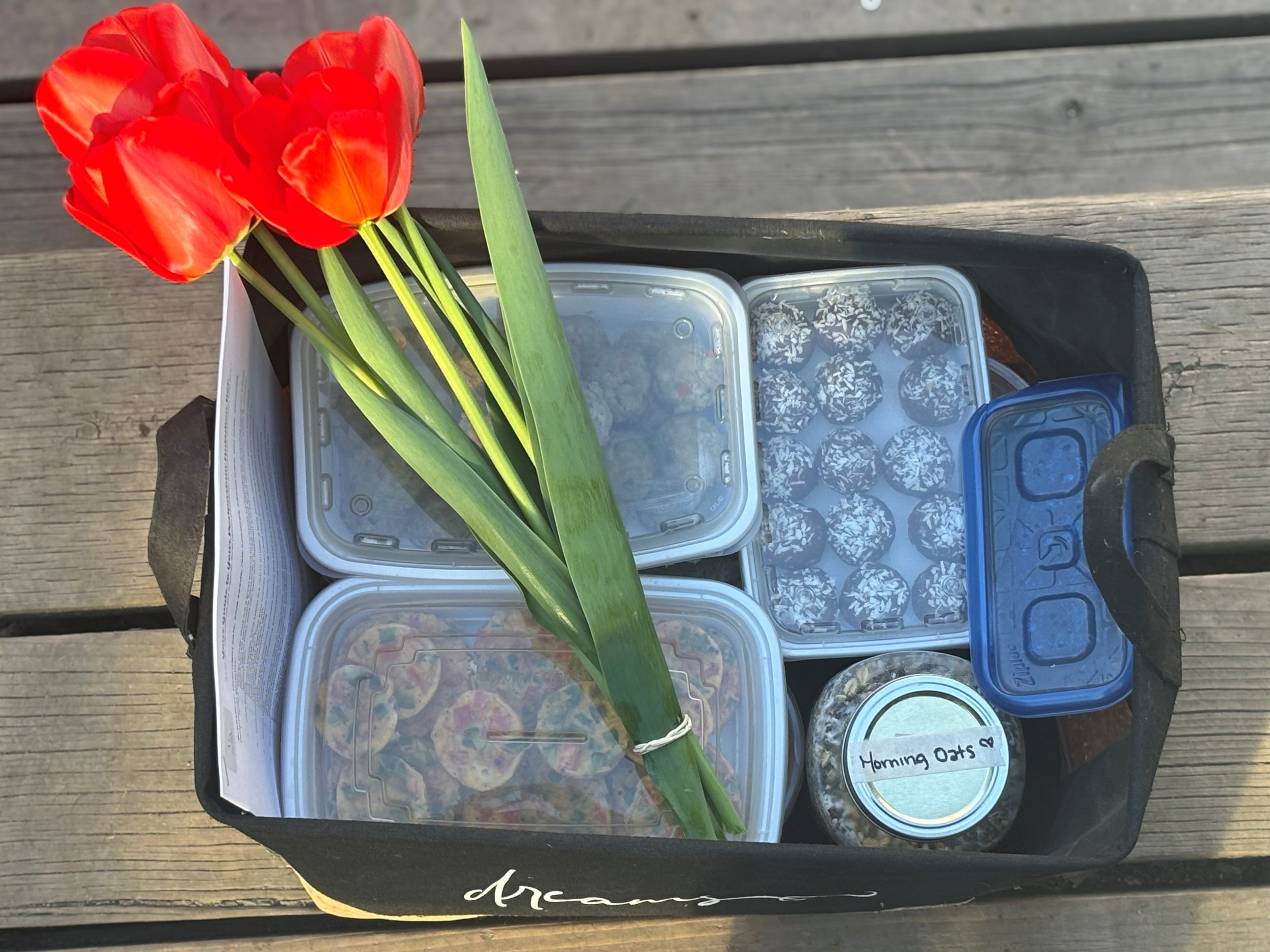 A weekly nutrition box delivered to a client that includes, bone broth, homemade lactaction bliss balls, egg bites, overnight oats, fresh picked flowers.