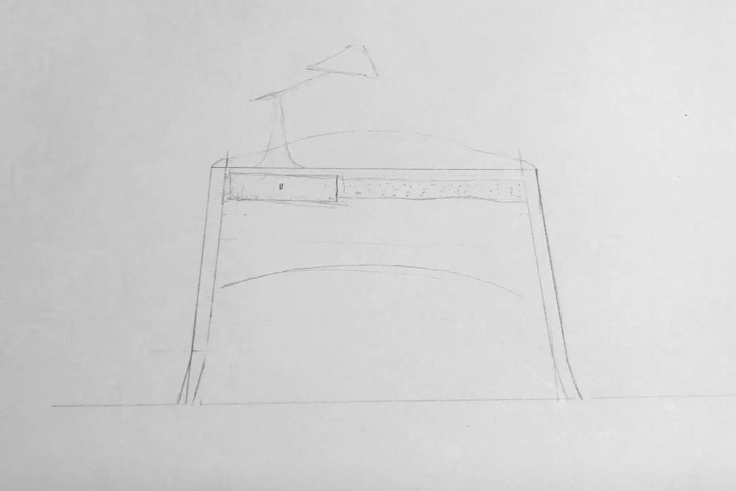 A simple pencil sketch of a writing desk with a curved stretcher, a drawer on the left side, and a small working lamp - furniture design development by Henry Crabb, West Cornwall