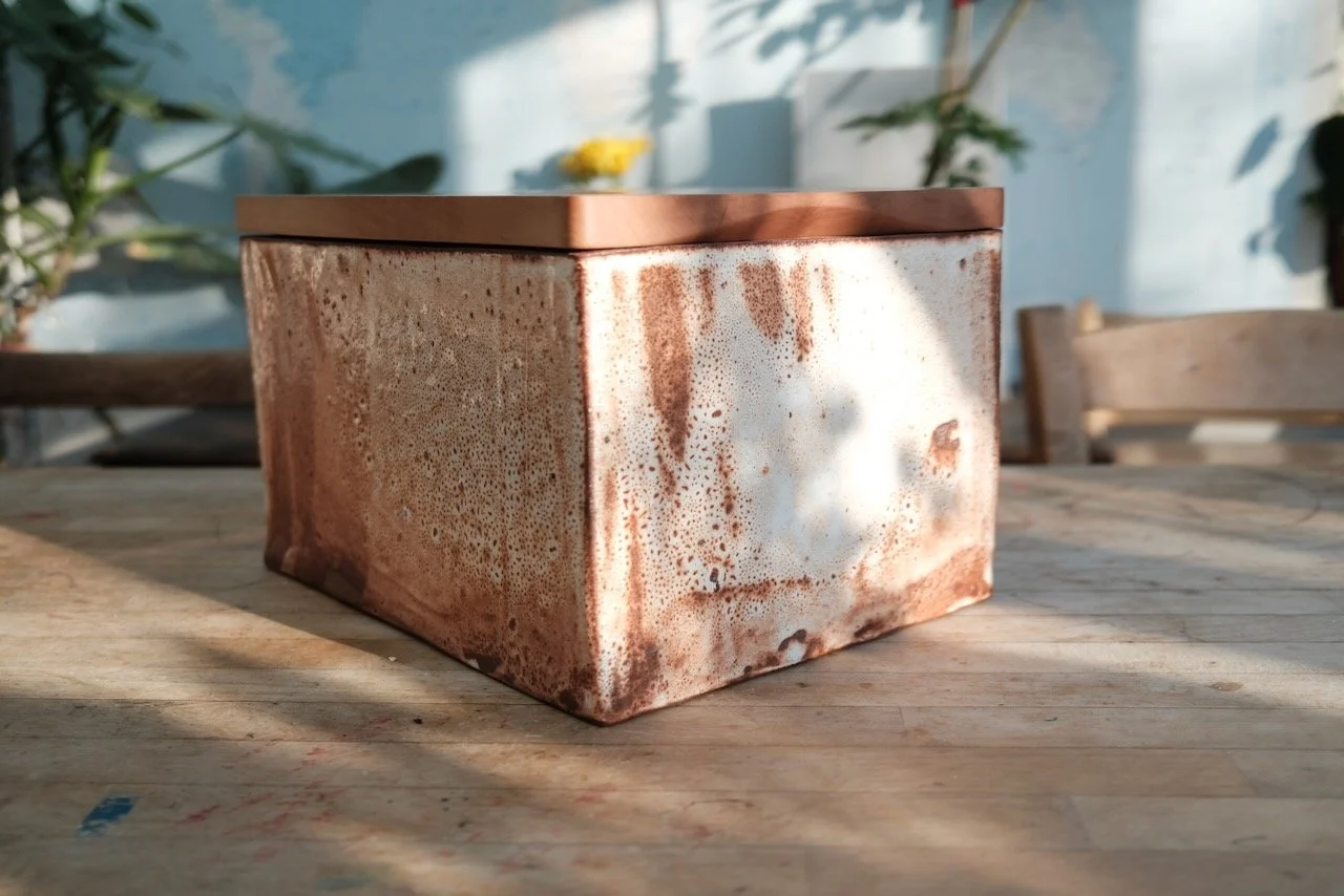 Handmade bread bin in shino-glazed Cornish clay with Swiss pear wood cutting board lid — three-quarter view showing full glaze, by Henry Crabb and Leach Pottery