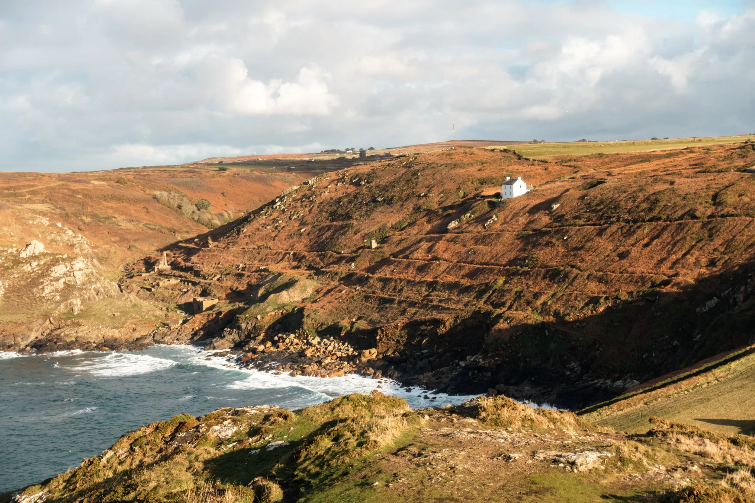 Bracken-covered cliffs and a white cottage above the Atlantic, West Penwith, Cornwall — the landscape surrounding Henry Crabb's workshop