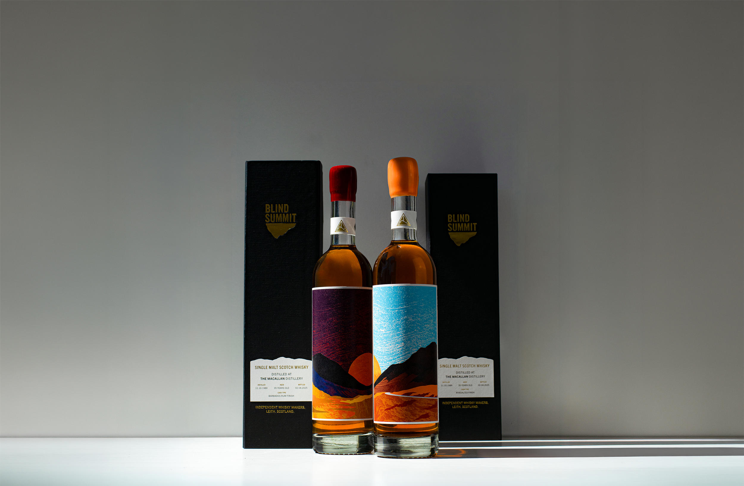 Two bottles of single Blind Summit whisky with black boxes behind them, featuring colorful landscape illustrations and labels from The Macallan Distillery.