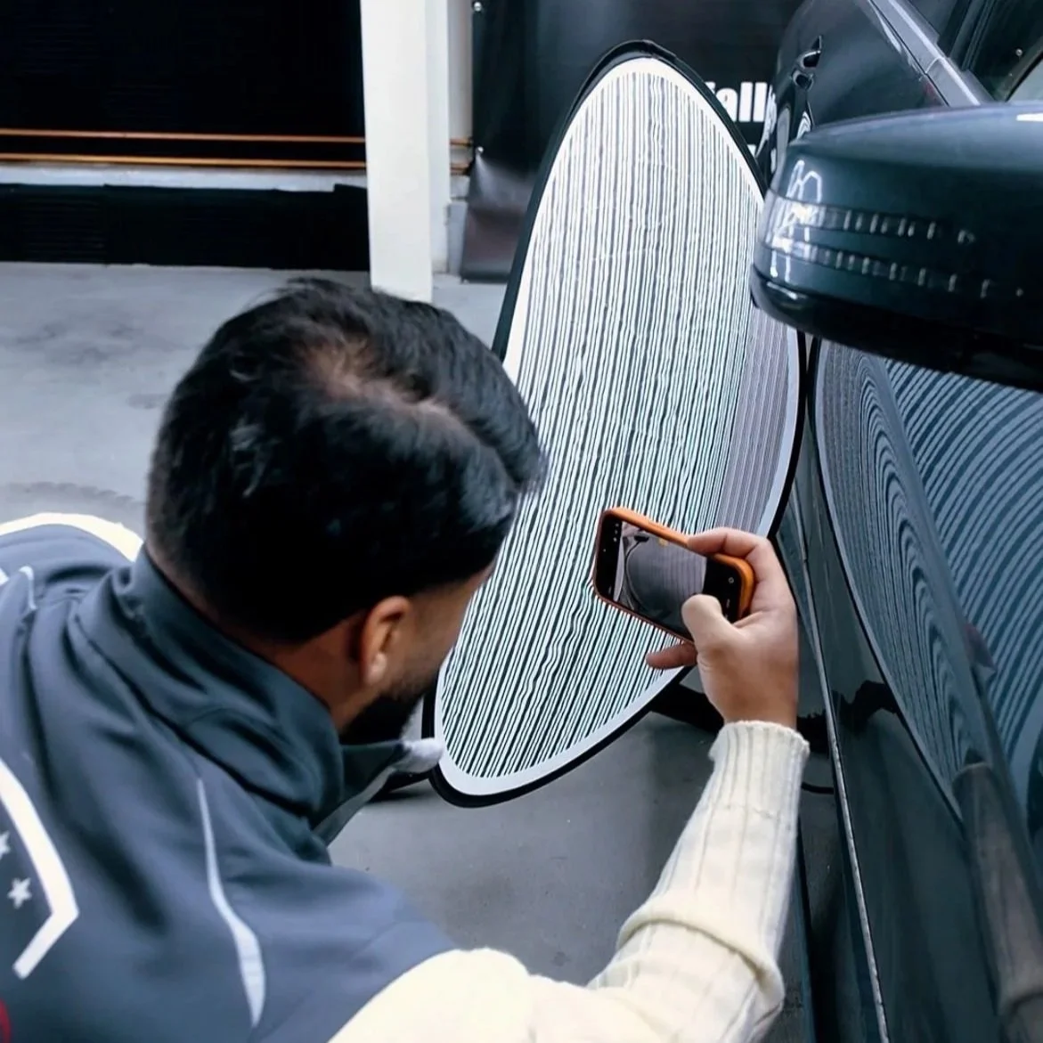 Mann filmt ein T-Shirt mit seinem Smartphone im Auto.