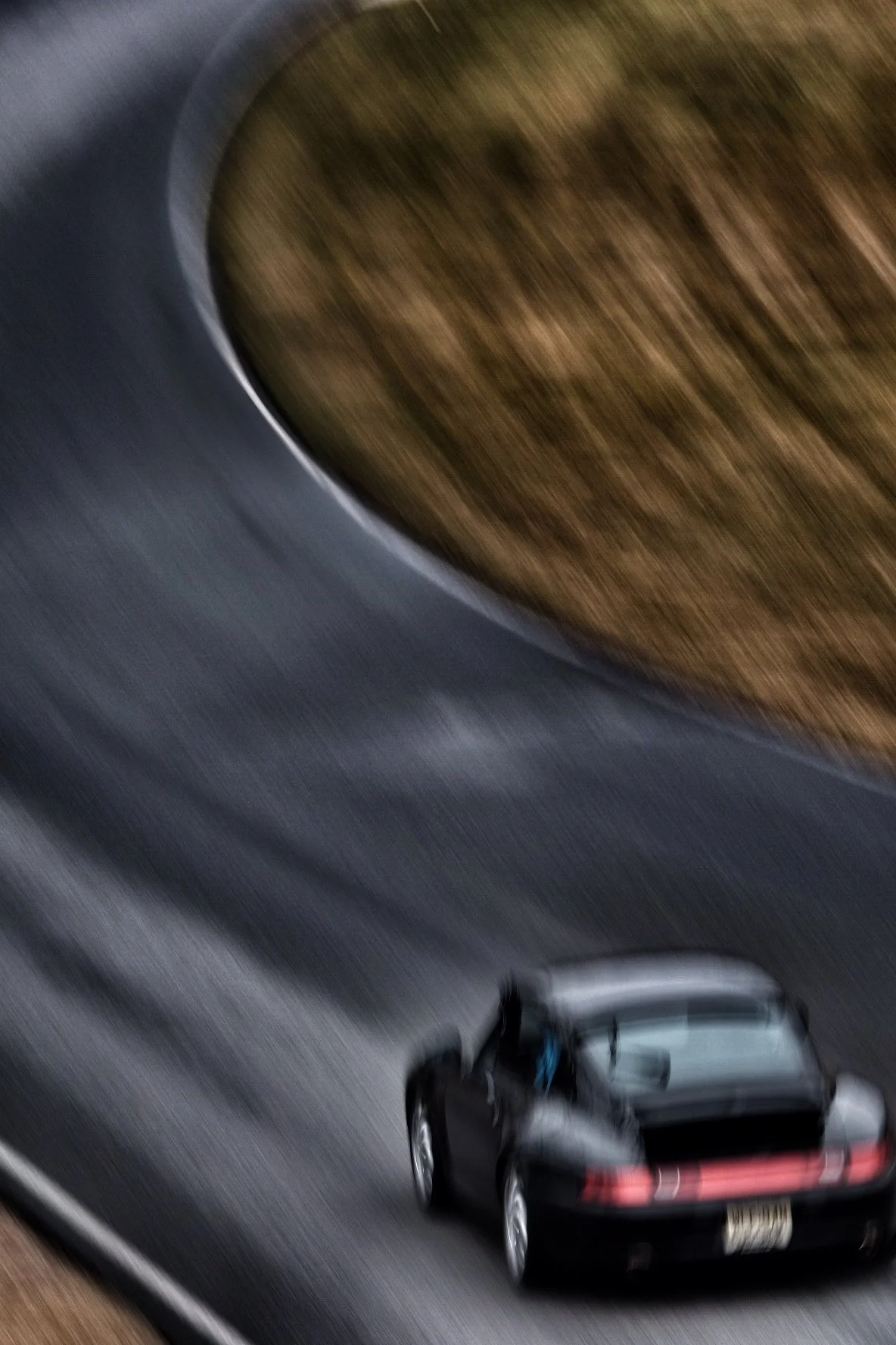 A black sports car driving on a curved road with a blurred background.
