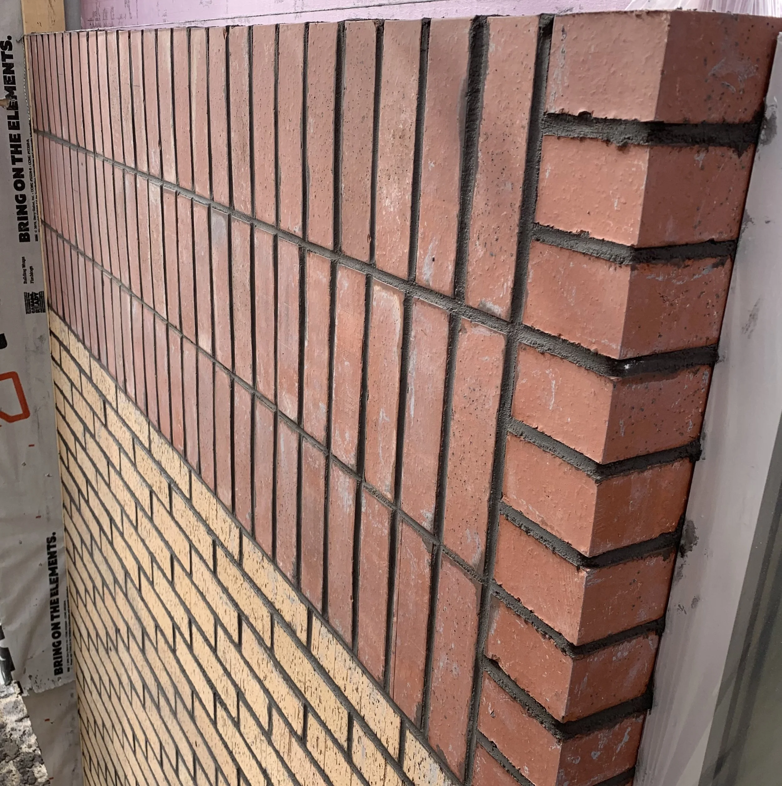 Close-up of a stack of red bricks with grey mortar lines, partially covered by a white sheet of paper with printed black text.