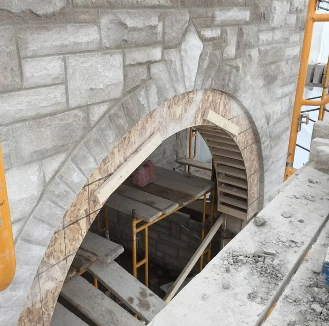 Construction site with a brick archway and scaffolding inside a building under construction.
