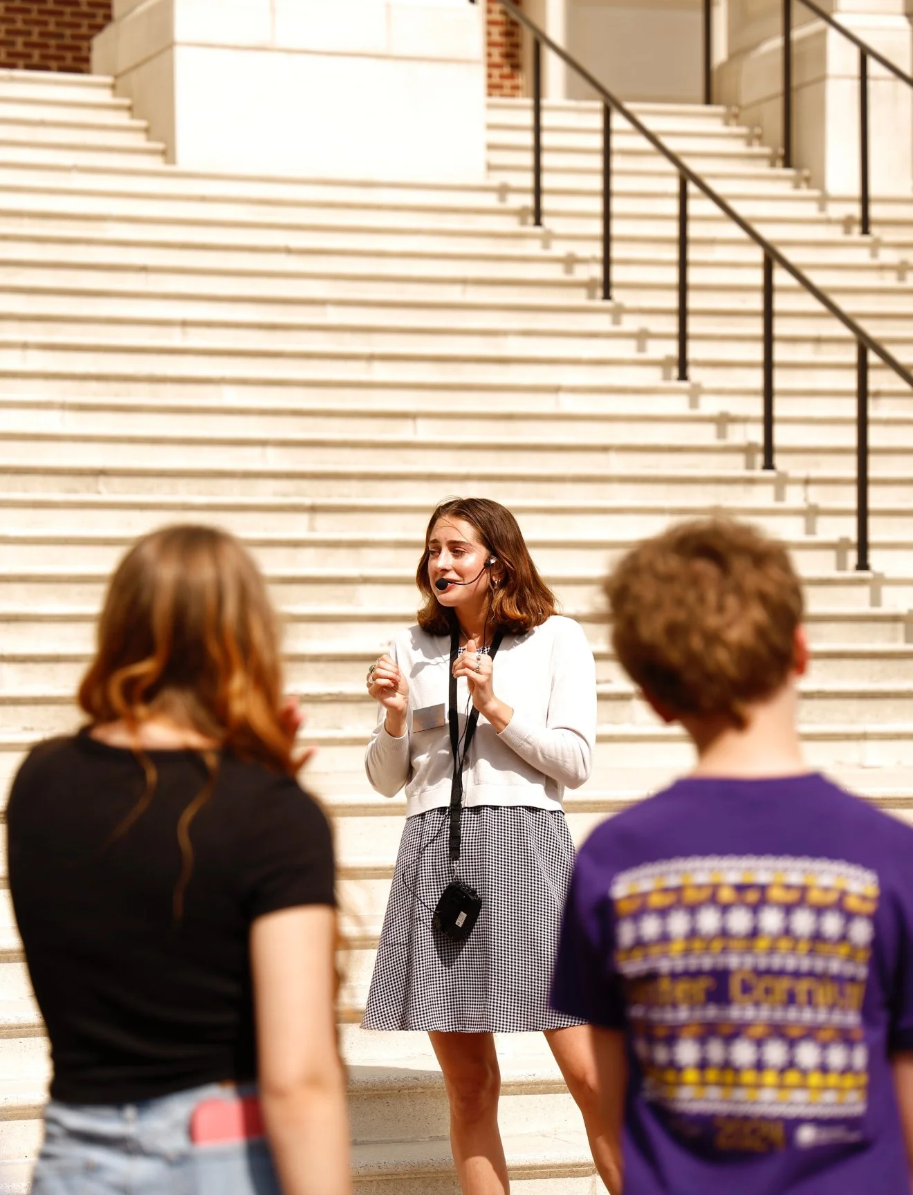 A tour guide speaking to two tourists on the steps of a building.