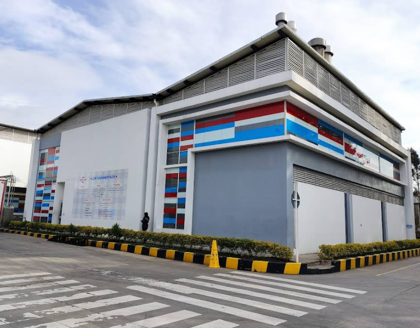 Modern building with colorful red, blue, and white design elements, located at a corner with a crosswalk in the foreground and a person standing near the wall.