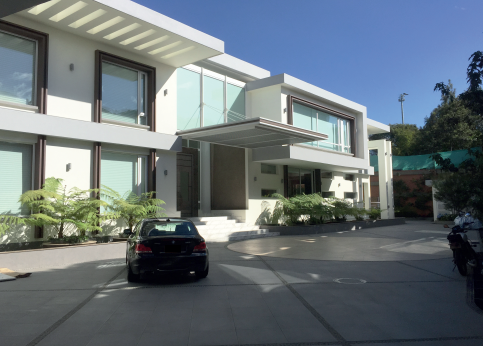 Modern multi-story residential building with large windows and a parking area with several cars.
