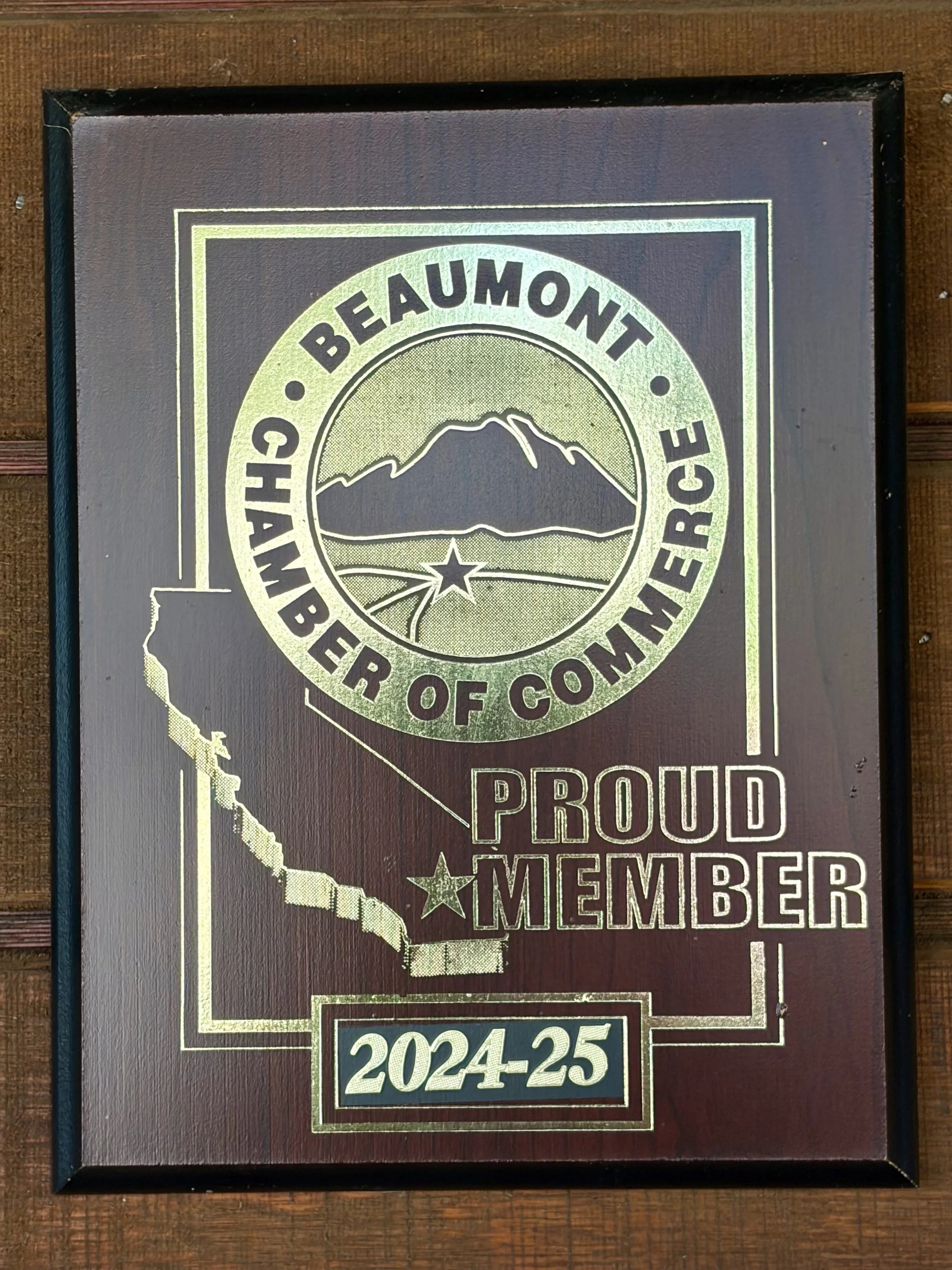 Framed sign featuring a map of California, a mountain range, a star, and text reading 'Proud Member 2024-25'.