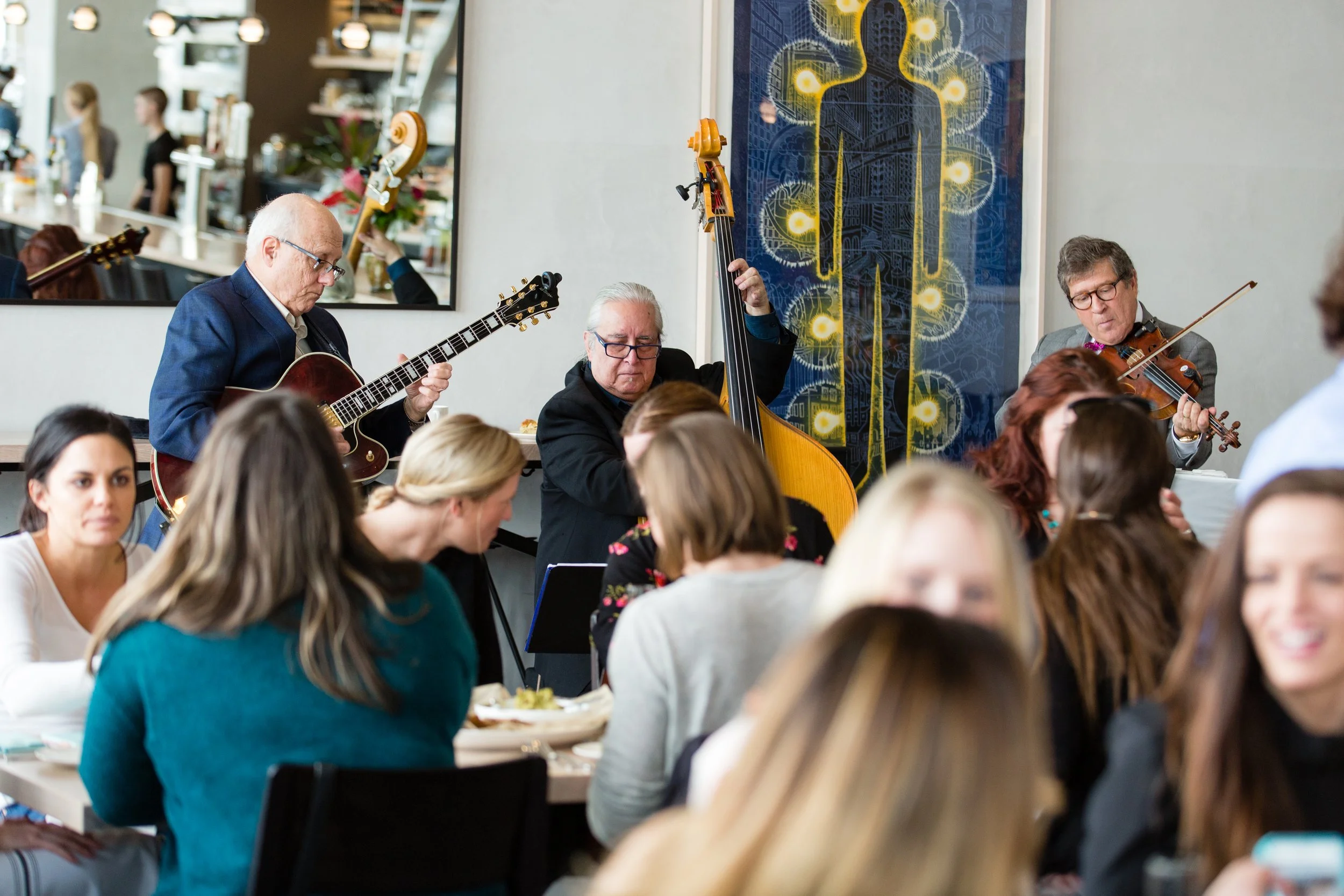 Musicians performing in a restaurant with an audience of people dining and enjoying the music.
