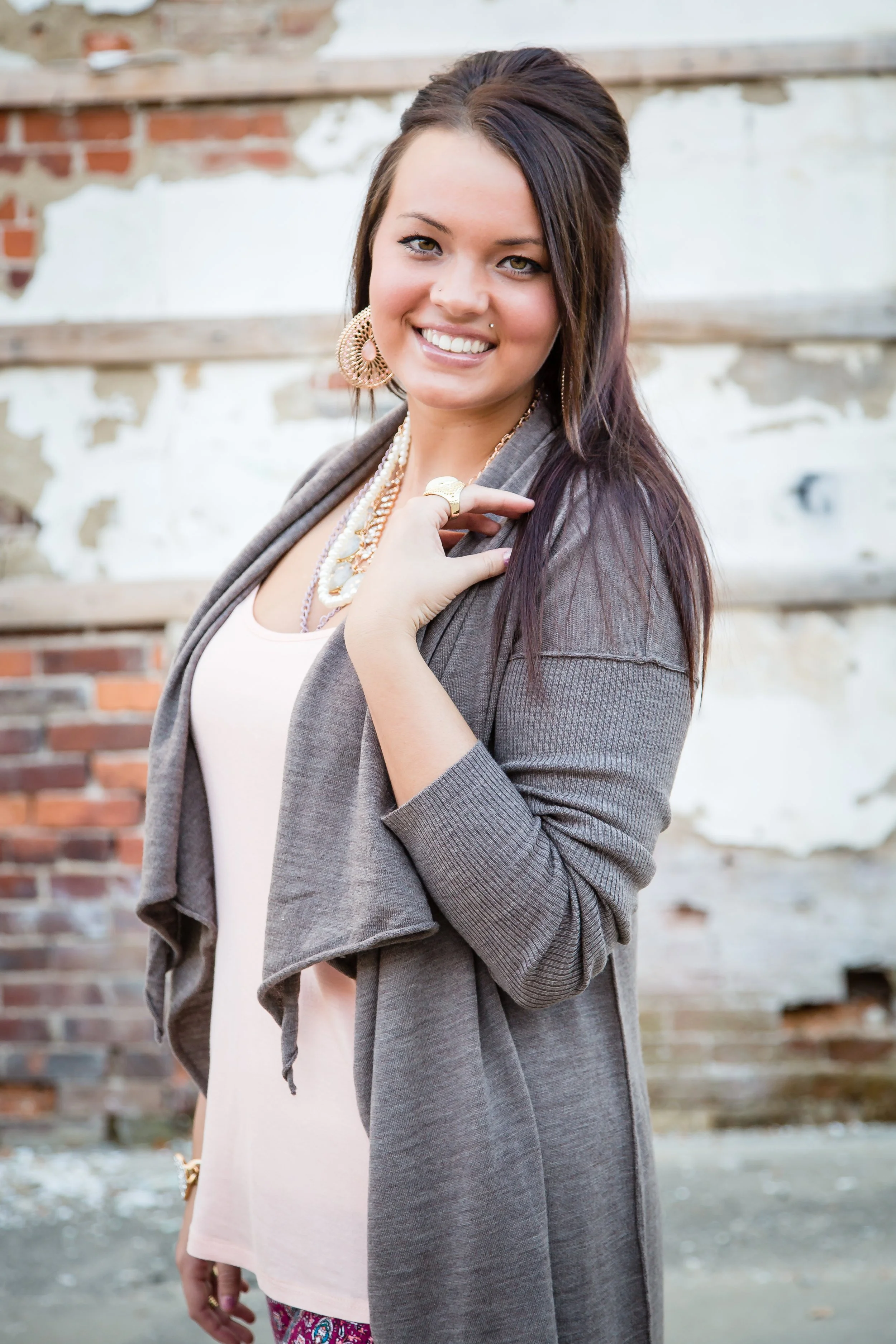 An artistic high school senior portrait session featuring a girl smiling and posing in front of an urban public art wall and weathered brick building in Muncie, Indiana.