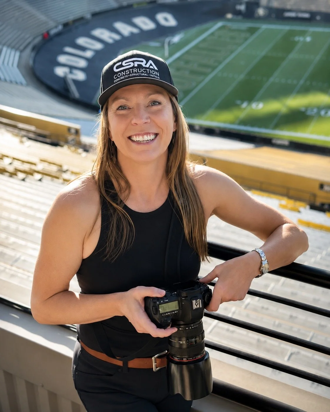 Photographer Lisa Doane holding her camera at Folsom Field during the CSRA Summit on the University of Colorado Boulder campus.