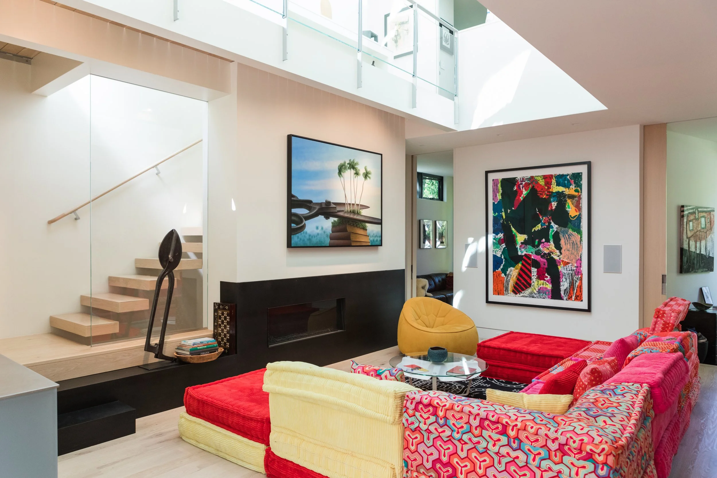 Modern living room with colorful furniture, artwork, and natural light.