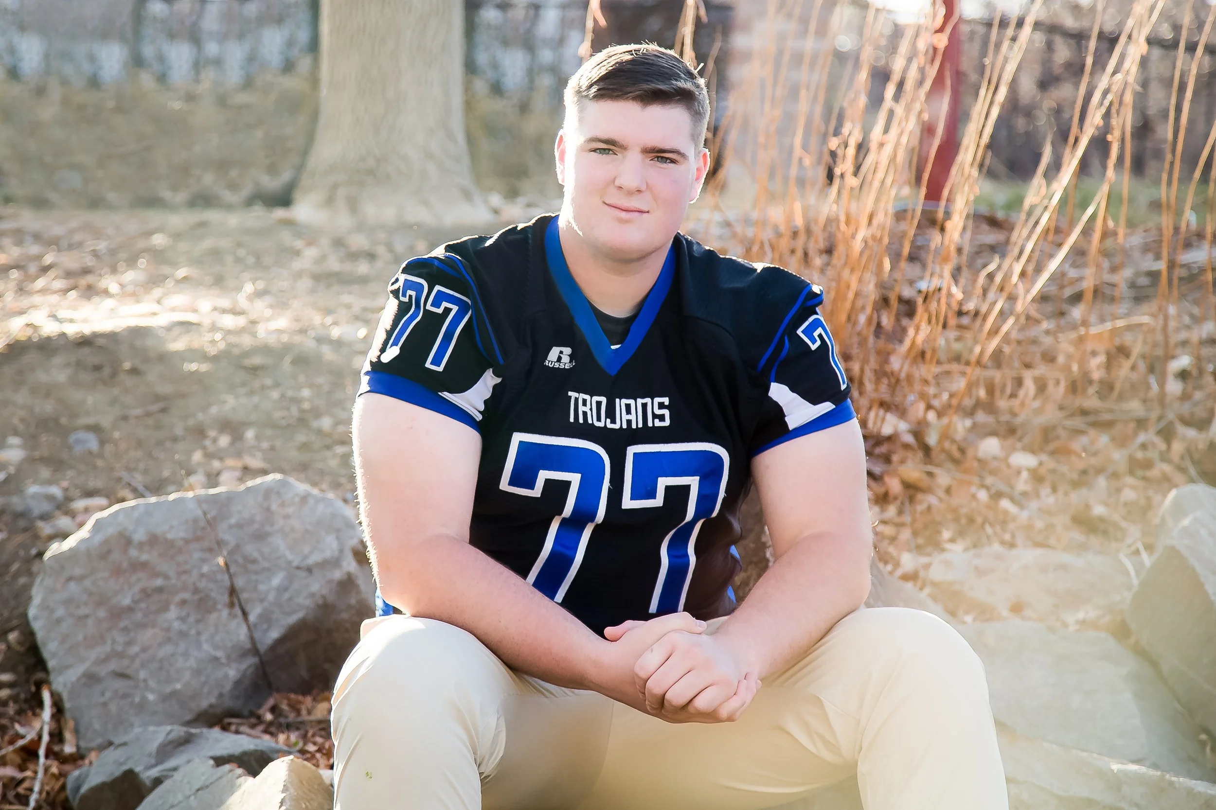 A high school senior portrait session of a football player wearing his jersey, captured on location in a natural outdoor setting near McIntosh Lake in Longmont, Colorado.