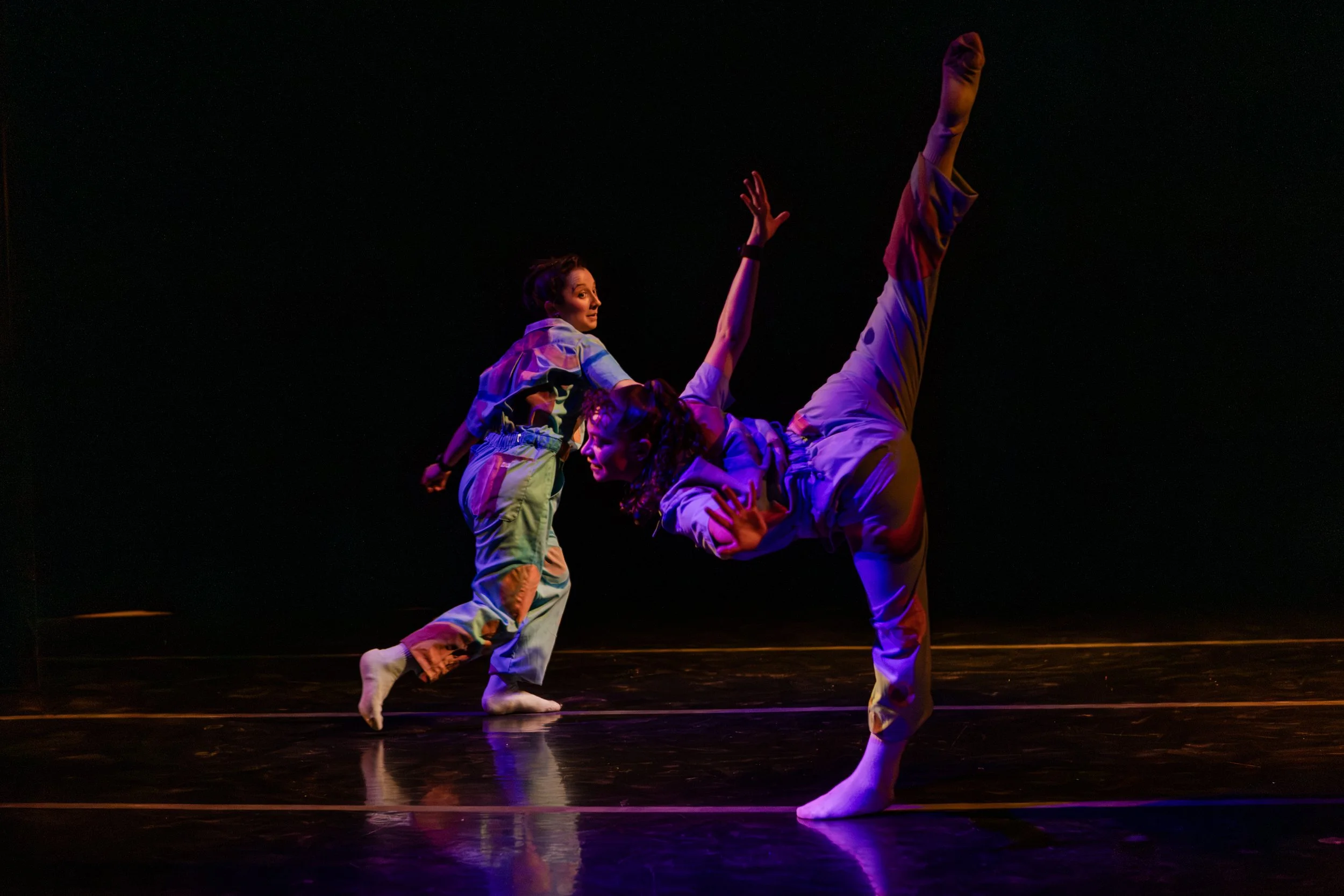 Professional performance photography by Lisa Doane Photography of the dynamic modern dance festival Dance Continua at The Spark in Boulder, Colorado. This energetic frame captures two dancers in distinctive multi-colored patterned outfits executing d