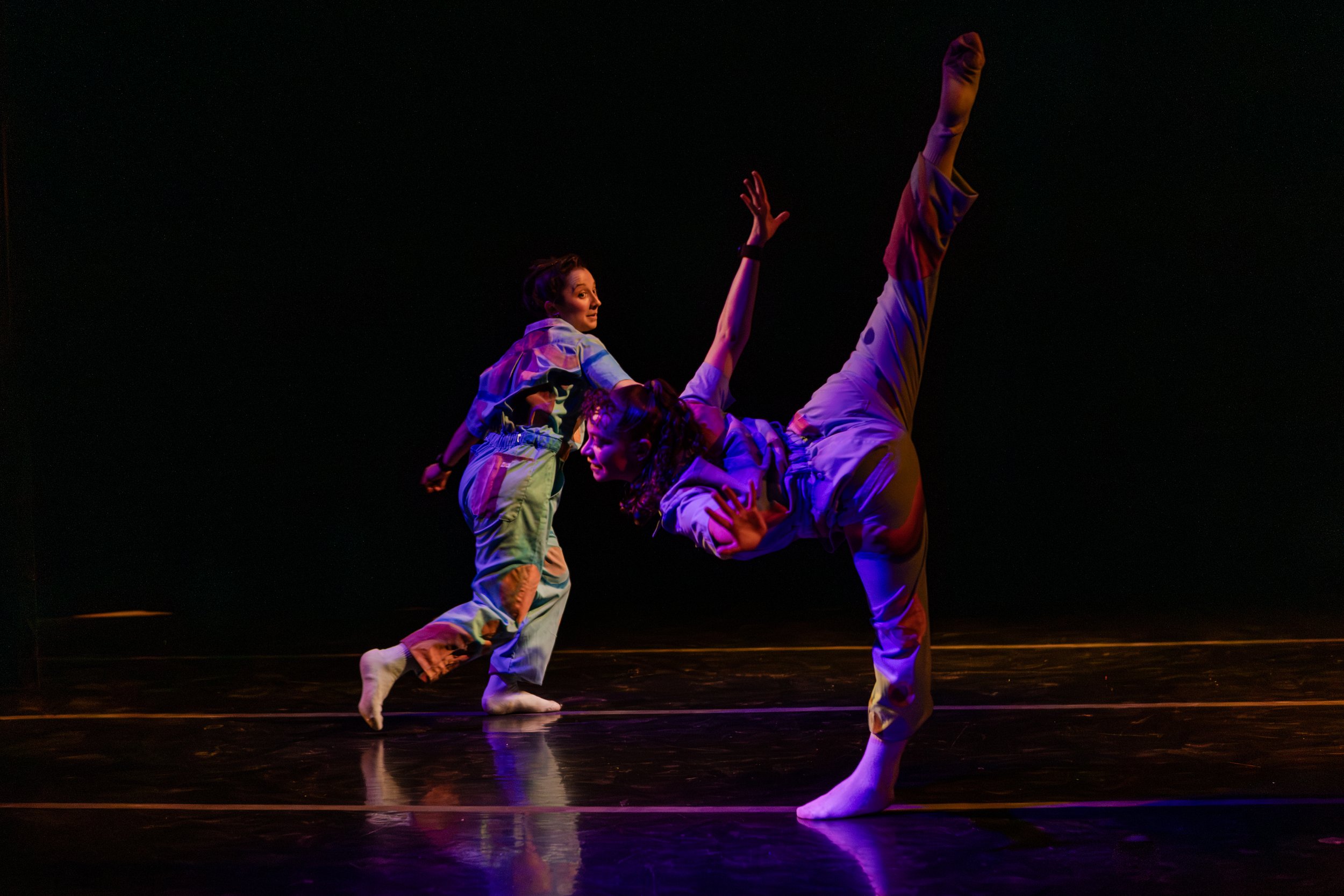Professional performance photography by Lisa Doane Photography of the dynamic modern dance festival Dance Continua at The Spark in Boulder, Colorado. This energetic frame captures two dancers in distinctive multi-colored patterned outfits executing d